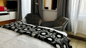 Une chambre d’hôtel avec un lit, un bureau avec un ordinateur, une chaise et une fenêtre avec des rideaux.
