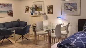 Una camera moderna con un tavolo da pranzo in vetro, una poltrona e un letto.