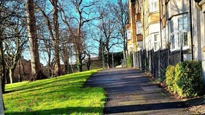 A residential street with houses on one side and a grassy area with trees on the other. - The Parkview House Wakefield - 31 Tuke Grove not 42 Please (Wakefield)