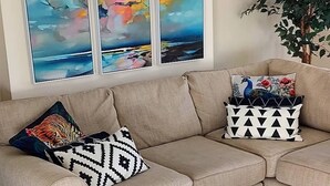 A beige sectional sofa with patterned cushions, a large abstract painting on the wall, and a potted plant. - The Parkview House Wakefield - 31 Tuke Grove not 42 Please (Wakefield)