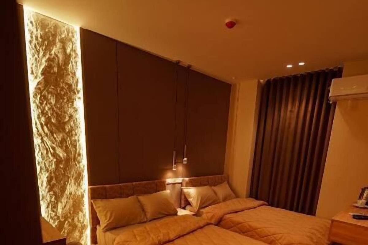 Une chambre d’hôtel avec un grand lit, une table de chevet, une chaise et un luminaire fixé au mur.