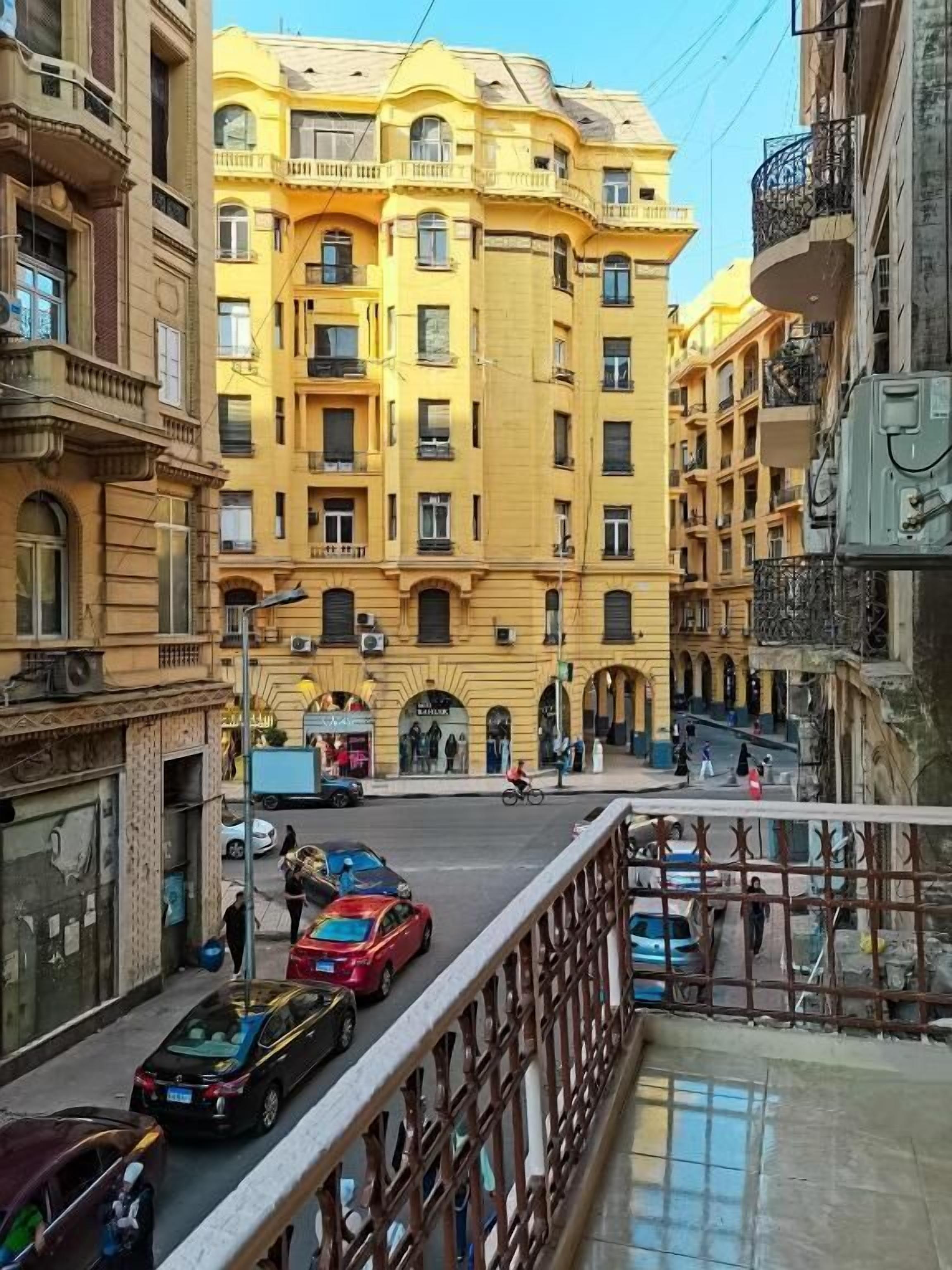 Un edificio amarillo de varios pisos con balcones y una calle en primer plano.