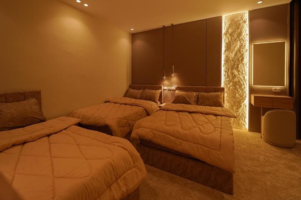 Una habitación de hotel con dos camas, un espejo grande y una lámpara fijada a la pared.