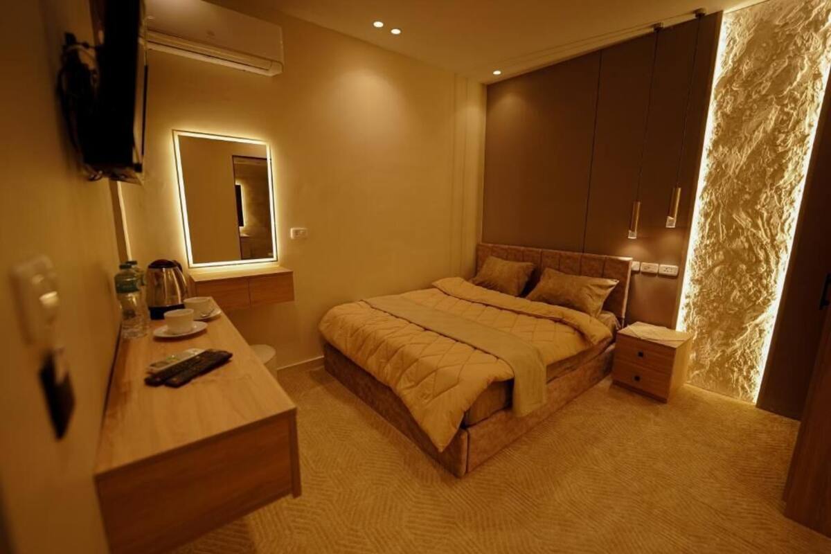 Une chambre à coucher avec un lit, une table de chevet et un miroir.