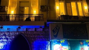 Un bâtiment doté d’un balcon, d’une enseigne Nike et d’une devanture de magasin ornée de diverses affiches.