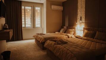 Habitación de hotel con dos camas, un ventanal grande, un equipo de aire acondicionado y un televisor sobre un mueble.