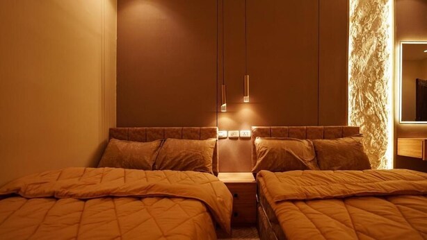 Une chambre d’hôtel avec deux lits, une table de chevet et un téléviseur fixé au mur.