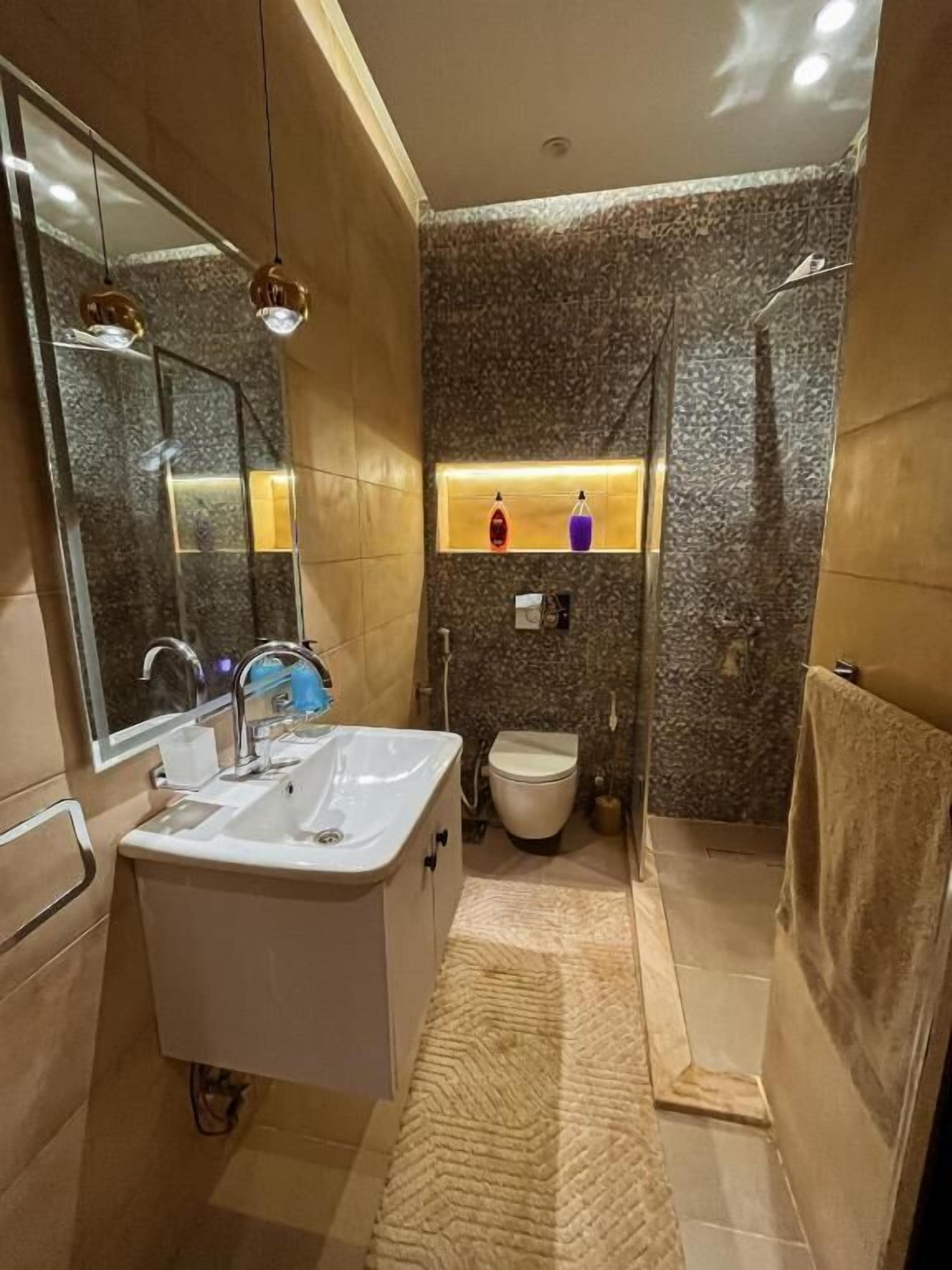 Un baño moderno con un espejo grande, un lavabo, un inodoro y una zona de ducha.