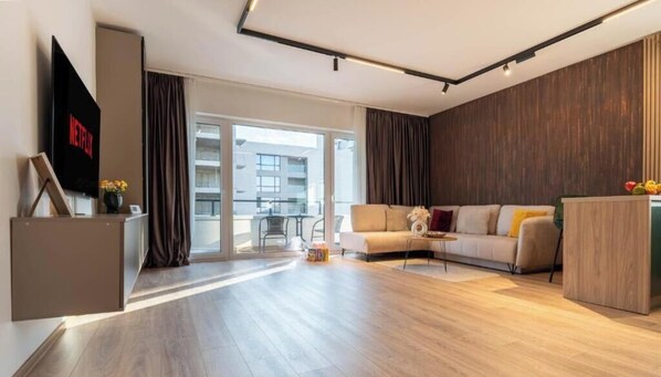 Un salon moderne avec un canapé, un téléviseur et un meuble en bois.