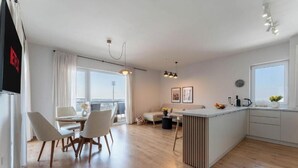 A modern kitchen with a central island, a dining area with chairs, and a large window offering a view. - MoHost Arena (Brașov)