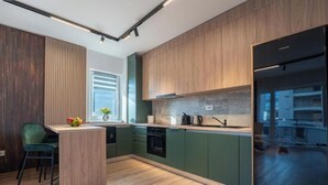 A modern kitchen with wooden cabinets, a built-in oven, and a stainless steel refrigerator. - MoHost Arena (Brașov)