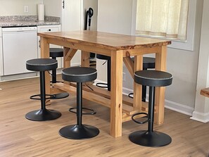 Eine Küche mit einem Holztisch und drei schwarzen Barhocker.