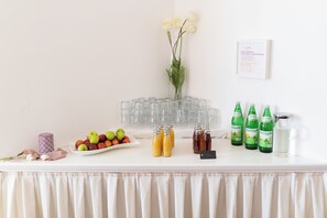 A buffet table with a variety of food and drink options, including fruits, juices, and bottles of water. - geislerAPPARTMENTS (Gramatneusiedl)