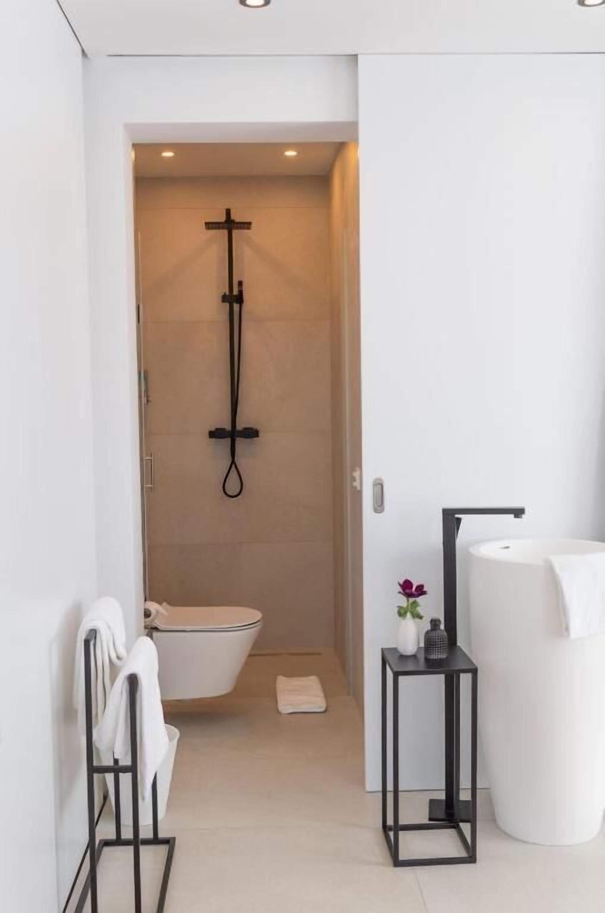 A modern bathroom with a toilet, a shower, and a sink.