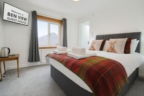 Una habitació d'hoste amb un llit, una taula de nit amb una tetera, una finestra amb cortines, i un cartell que diu "Welcome to BEN VIEW GUEST HOUSE".