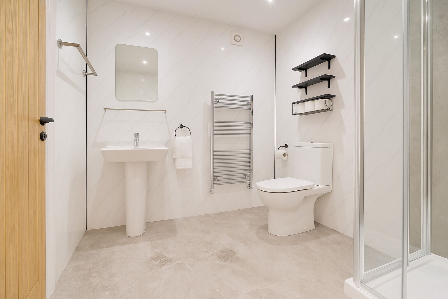 A modern bathroom with a white sink, toilet, and glass shower enclosure.