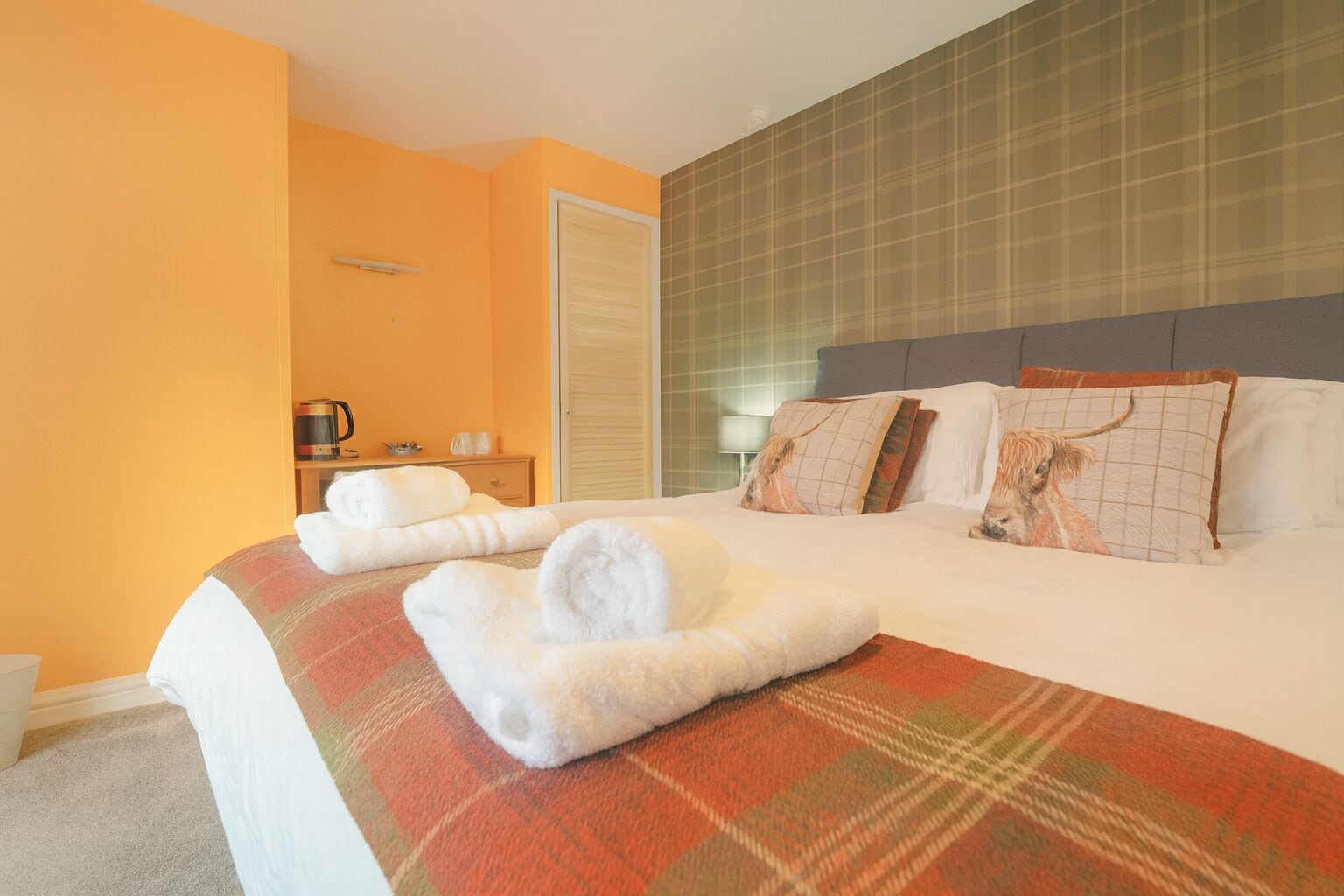 A hotel room with a bed, a nightstand, a lamp, and a window.
