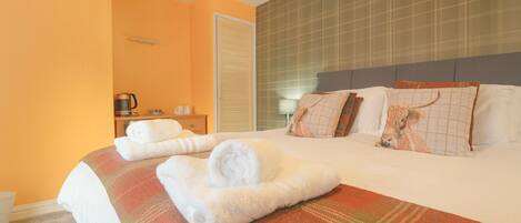 A hotel room with a bed, a nightstand, a lamp, and a window.