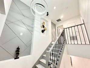 Eine moderne Treppe mit geometrischem Wanddesign und minimalistischer Geländerkonstruktion.