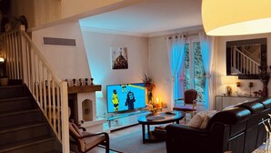 Un salon moderne avec un escalier, un téléviseur à écran plat, un canapé et un coin repas.