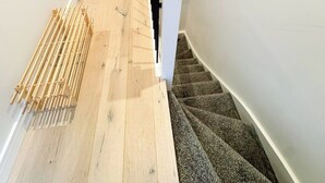 A staircase with wooden flooring and a white handrail. - Stylish Penthouse in Willesden, Scrubs Lane (London)