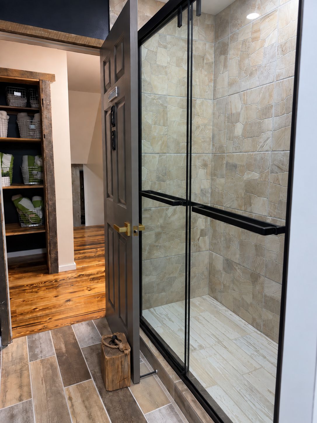 Une salle de bain moderne dotée d’une douche à parois de verre, d’un plancher en bois et d’une étagère intégrée avec des paniers de rangement.