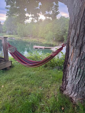 Un hamac suspendu entre deux arbres, une jetée en bois et un lac paisible.