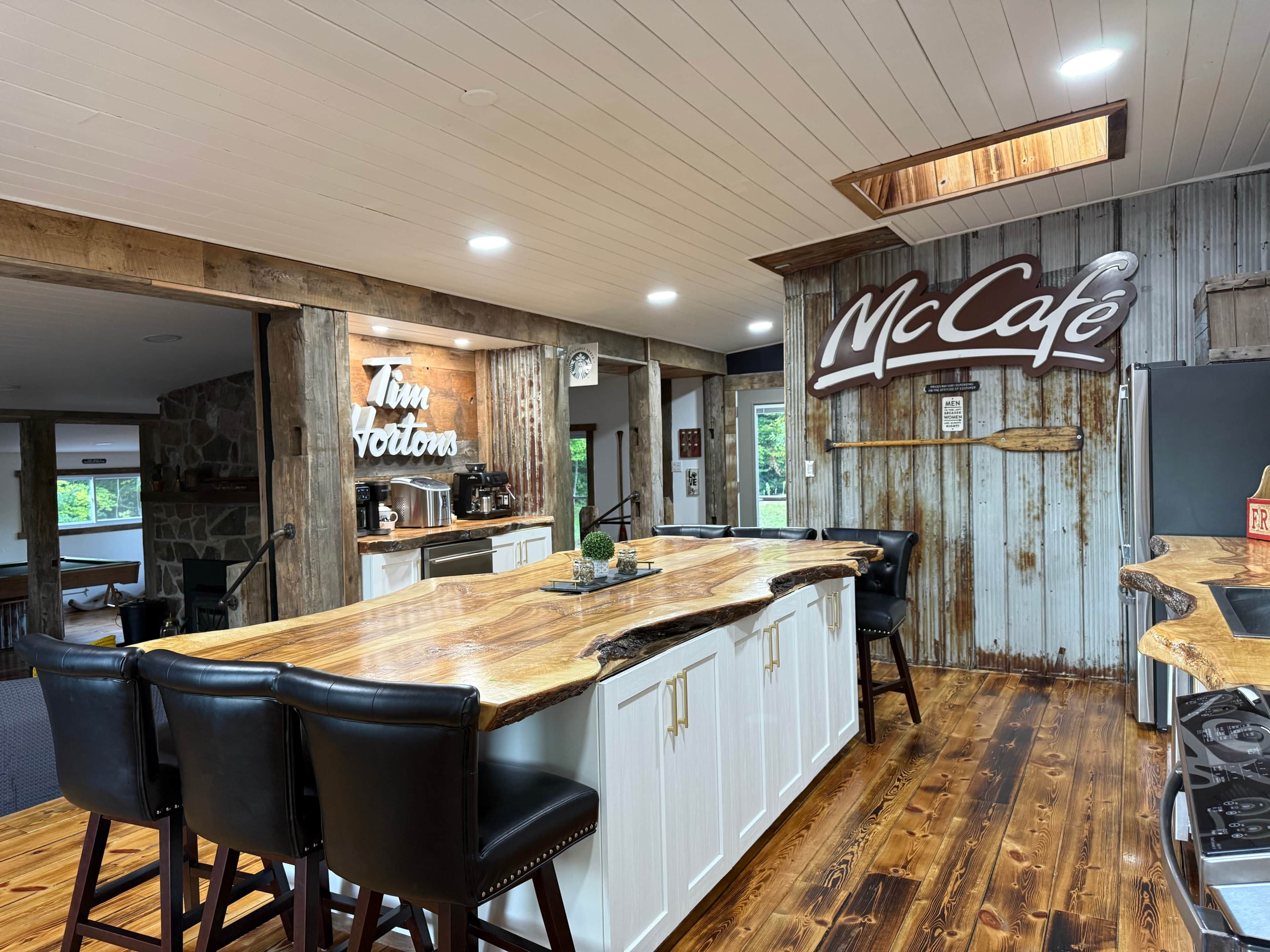 Tilava keittiö, jossa on suuri keittiösaareke, kivinen takka ja McCafe-kyltti.