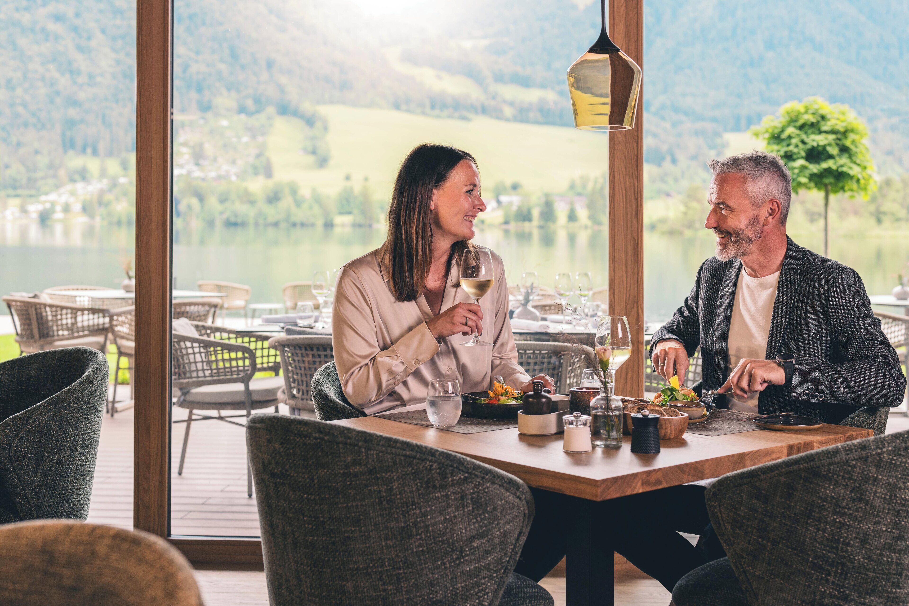 Une table à manger avec des chaises, une vue sur un lac et un paysage montagneux en arrière-plan.
