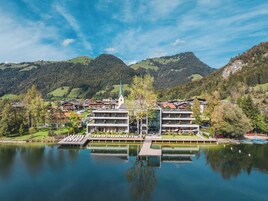 Un hotel moderno junto al lago, con un edificio central de varios pisos y un muelle que se adentra en el agua.