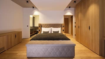 A modern bedroom with a large bed, wooden wardrobe, and a built-in bench.