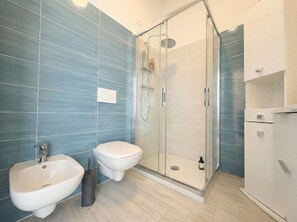 Ein modernes Badezimmer mit Duschkabine aus Glas, einem Bidet und einer Toilette.