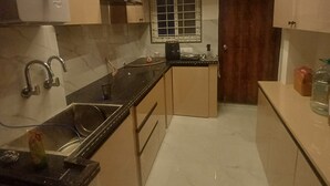 Une cuisine moderne avec un plan de travail noir, un évier en acier inoxydable et des meubles de couleur beige.
