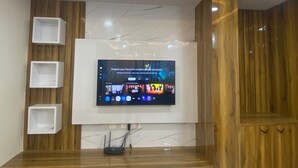 Un salon moderne avec un téléviseur fixé au mur, des lambris en bois et des étagères intégrées.