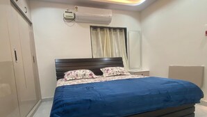 Une chambre à coucher comprenant un lit, une armoire, un appareil de climatisation et une fenêtre avec des rideaux.