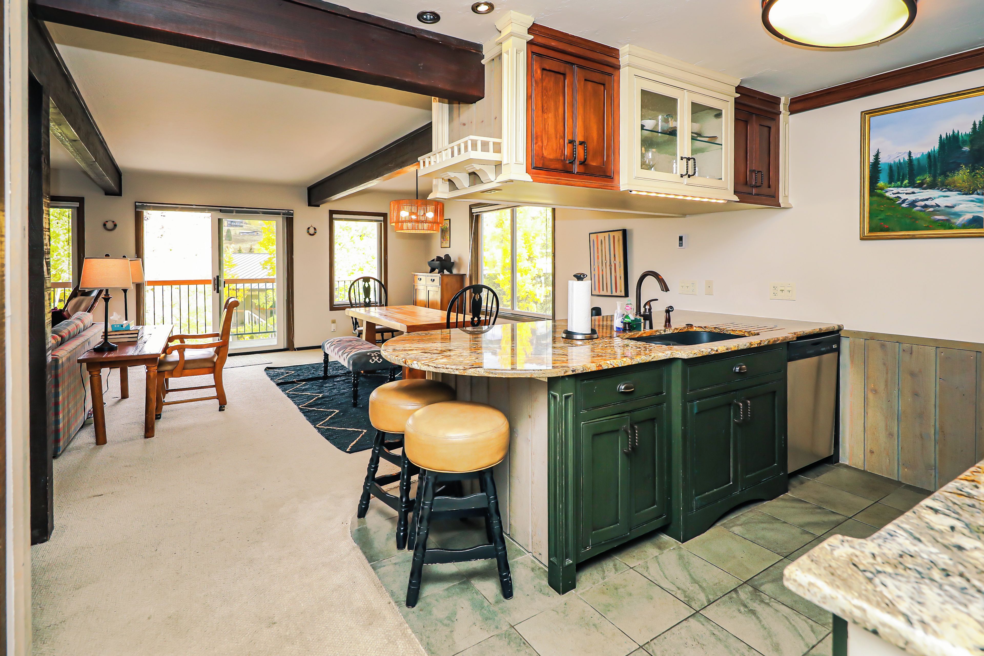 A kitchen with a large island, green cabinets, and a dining area with a sofa and chairs.