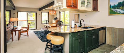 A kitchen with a large island, green cabinets, and a dining area with a sofa and chairs.