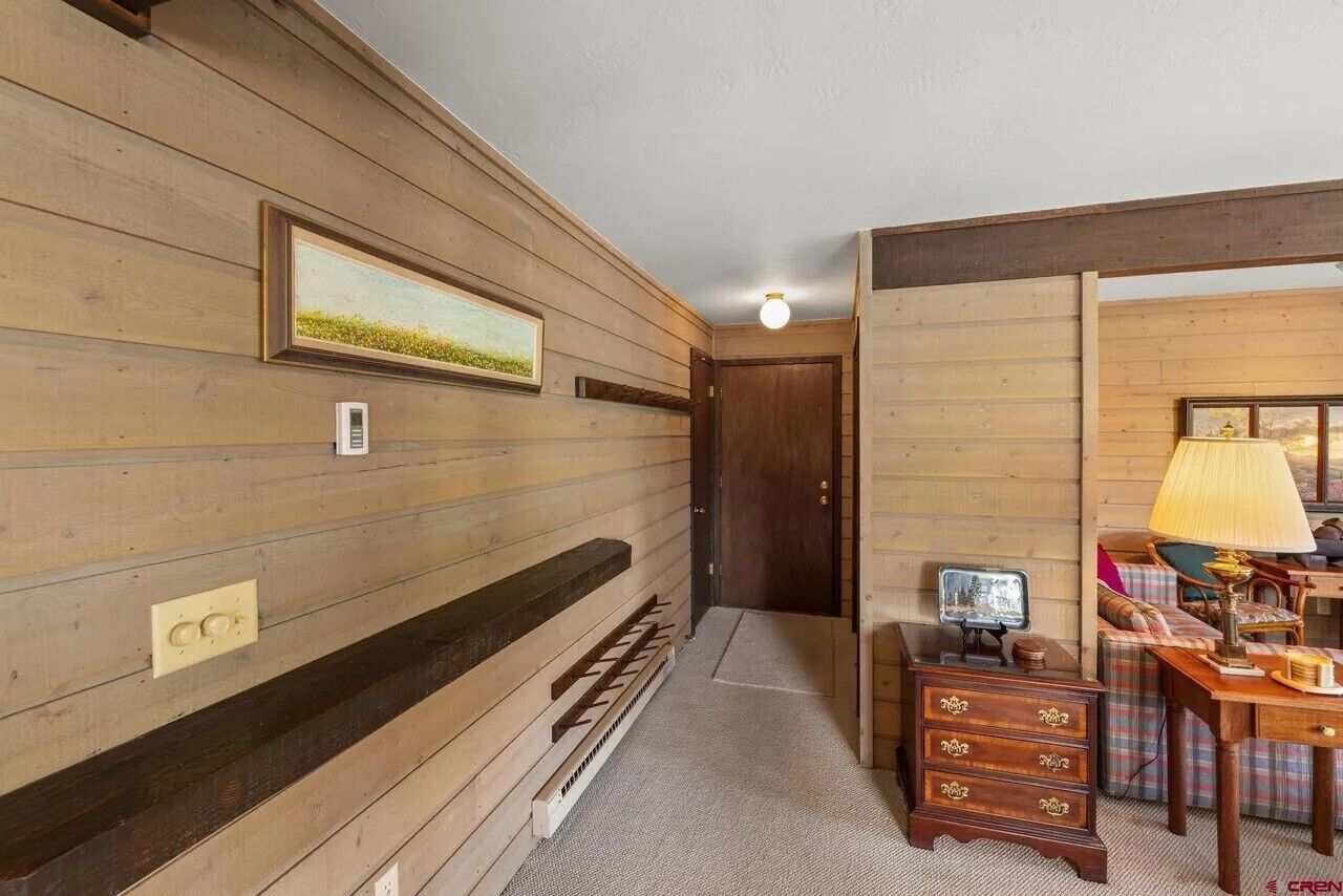 Un interior de madera con un cuadro enmarcado, una lámpara y una pequeña mesa.