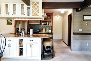 Una cucina con isola centrale, mobili bianchi e backsplash con motivo a spina di pesce.