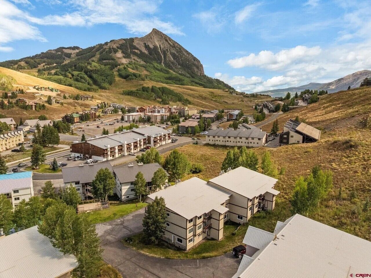 Zona residencial con varios edificios de apartamentos, una montaña destacada al fondo y un cielo despejado.