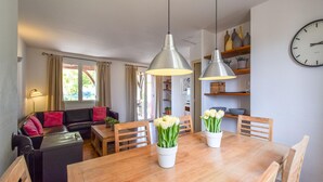 Een eetruimte met een houten tafel, stoelen en twee witte bloevazen.