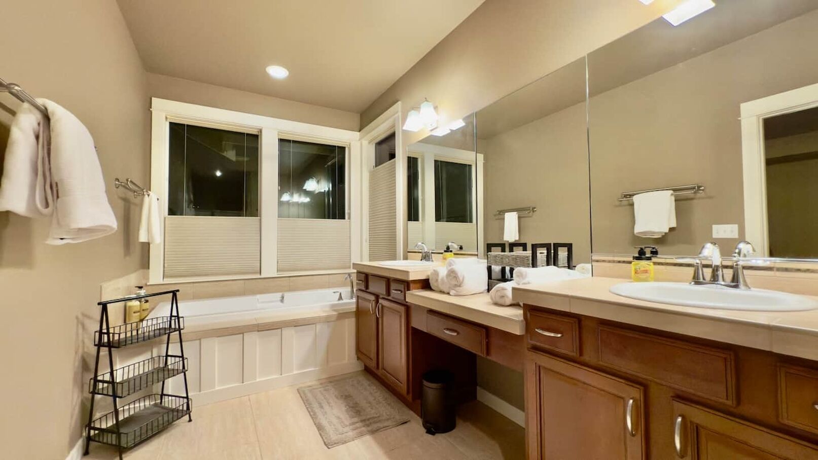 A modern bathroom with a bathtub, two sinks, and a large mirror.