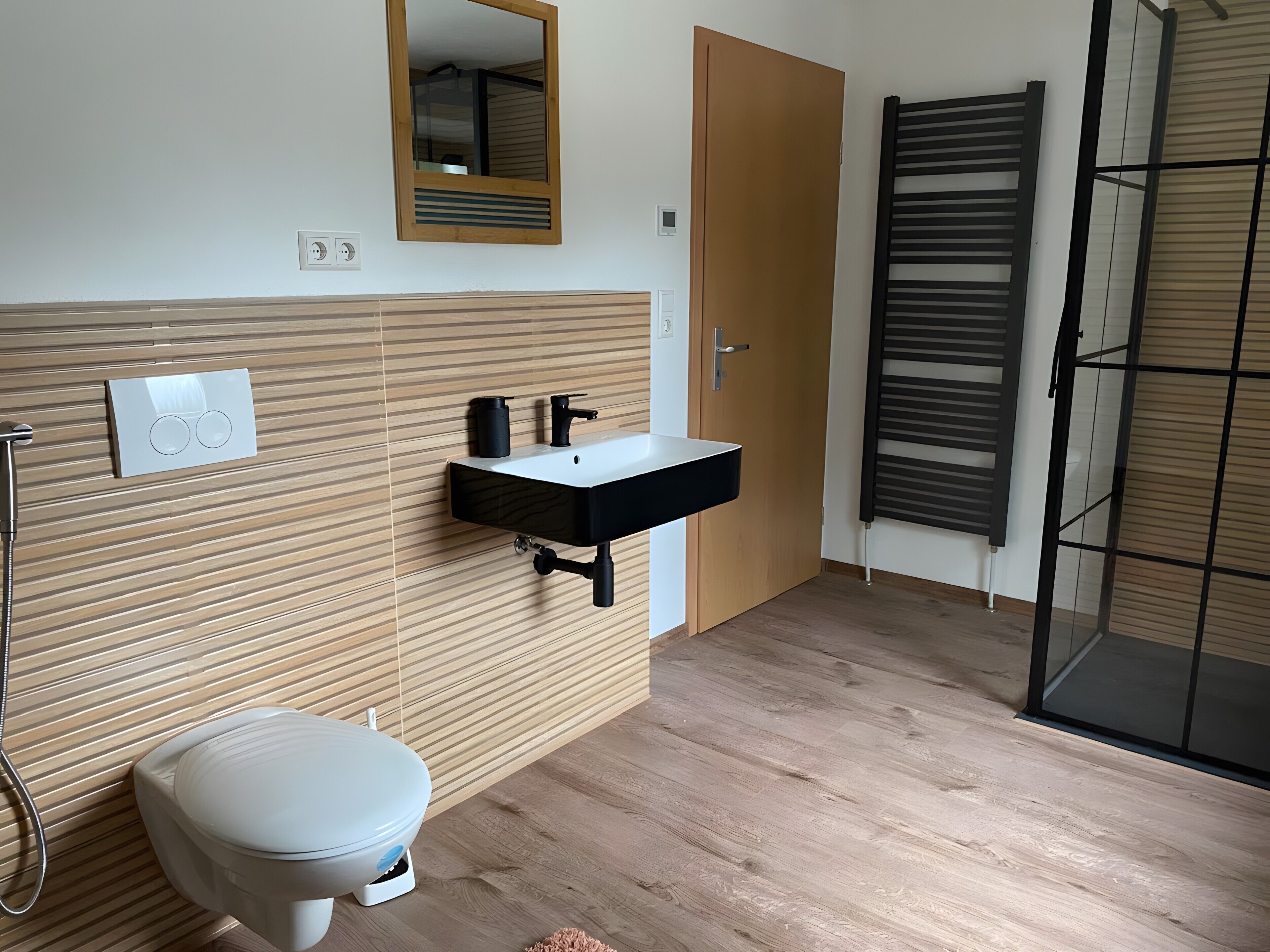 A modern bathroom with a toilet, sink, shower, and a mirror.