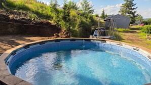Ein Schwimmbecken im Freien mit einer umlaufenden Holzterrasse.