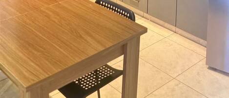 A modern kitchen with grey cabinets, a wooden dining table, and a built-in oven.