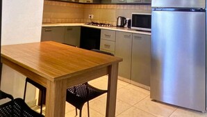 Une cuisine moderne avec une table et des chaises en bois, des appareils en acier inoxydable et des meubles de couleur claire.
