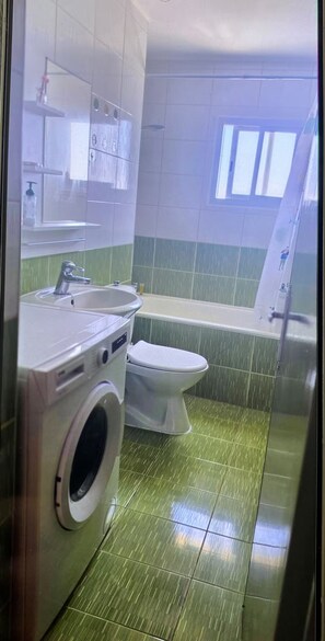 Ein Badezimmer mit Waschmaschine, Toilette und Badewanne.