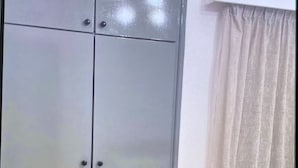 Une pièce avec une armoire grise, un climatiseur blanc et un plancher en bois.