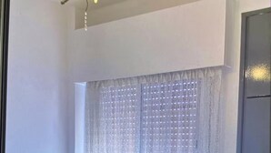Une chambre à coucher avec un lit, une tête de lit en bois, un lustre et une fenêtre ornée de rideaux légers.
