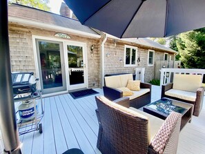 Un patio techado con mobiliario de mimbre, una parrilla y un tanque de propano Blue Rhino.
